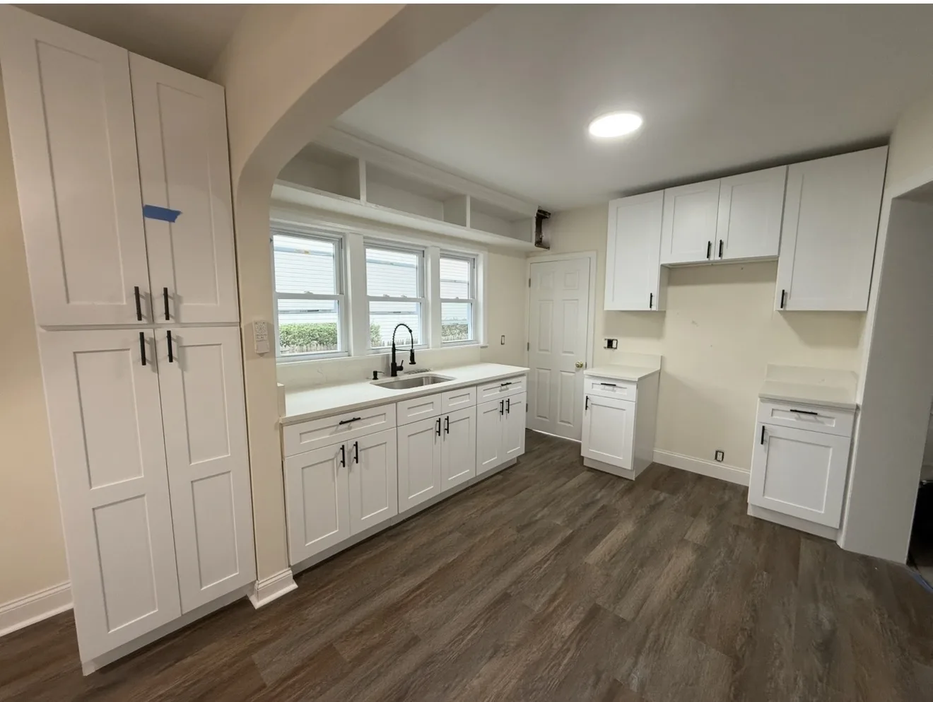 Renovated kitchen with white cabinets and wood floor
